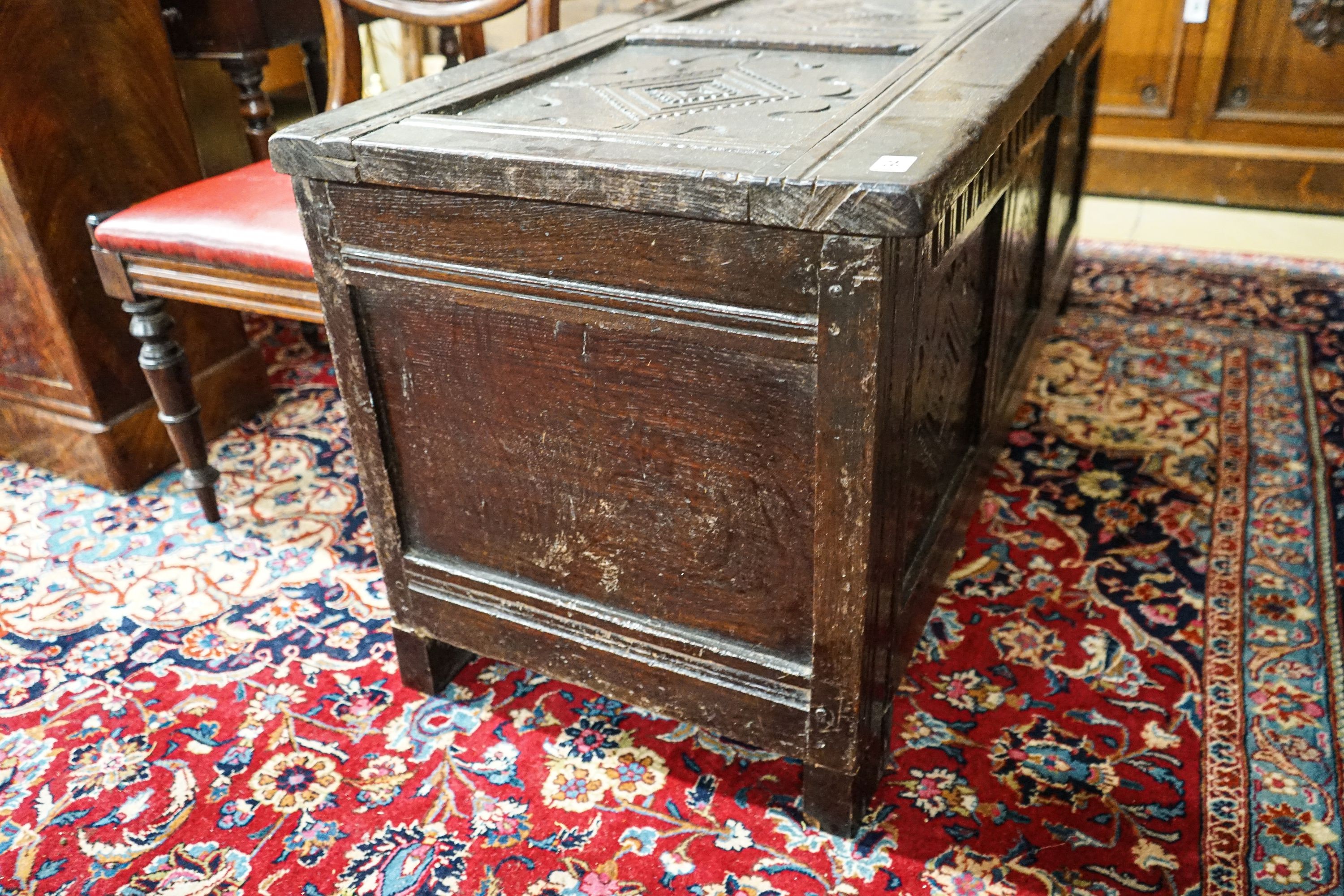 A late 17th/early 18th century carved and panelled oak coffer with hinged lid, width 136cm, depth 51cm, height 58cm